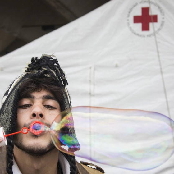 Man klädd i mössa blåser såpbubblor