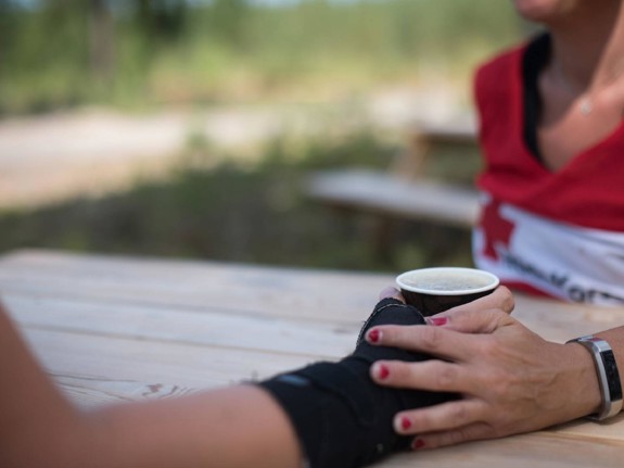 Stödjande hand på hand med kaffekopp