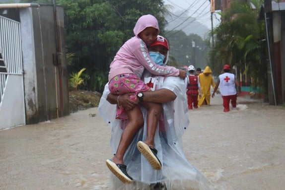 Flicka bärs genom vattenmassor i Guatemala