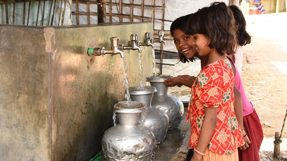 Flickor fyller på med rent vatten i flyktingläger.