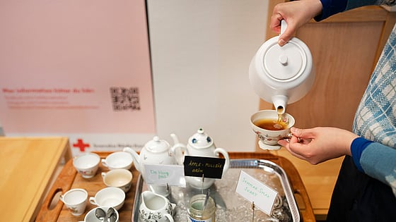 En person häller upp te från tekanna.