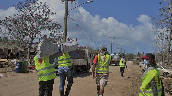 Volontärer bär säckar på en väg.