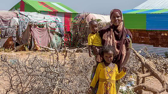 Mamma och barn framför tält.