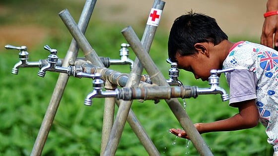 Pojke dricker vid vattenbrunn