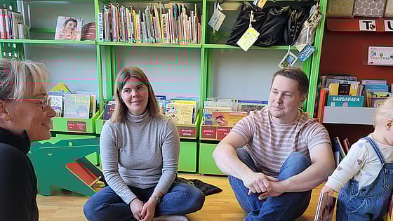 Föräldrar sitter på golvet medan deras barn leker intill.