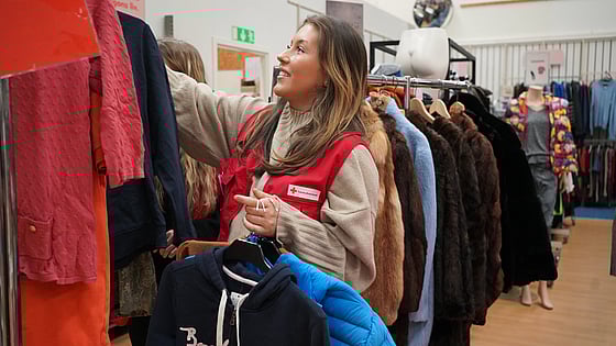 Praktikant-Moa-hänger-kläder-i-Röda-Korset-second-hand-butik