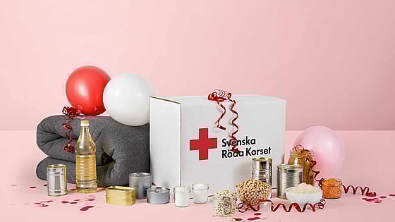 Ett matpaket och ullfilt från Röda Korset täckt i serpentiner, ballonger och konfetti.