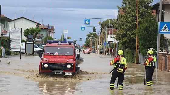 Män och bil på översvämmad gata i Italien