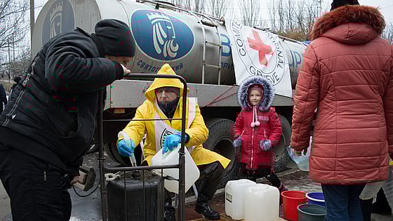 Liten flicka och vuxna med vattendunkar