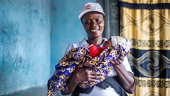 Kvinna från Röda Korset håller i bebis.