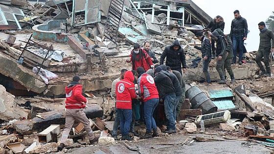 Röda korset volontärer tar ut människor ur raserat ut.