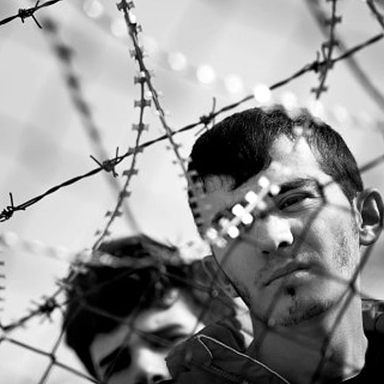 Två personers ansikten bakom taggtråd