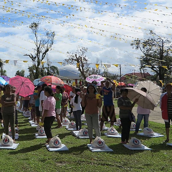 Flera personer under färgglada paraplyer och vimplar