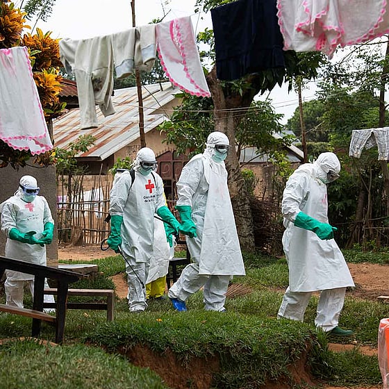 Människor i skyddsdräkt går i by