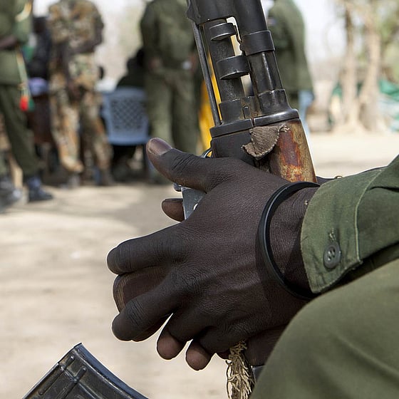 Soldathänder som håller i ett vapen.