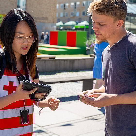 En värvare i Röda Korset-kläder visar innehåll på sin tablet för en potentiell givare.