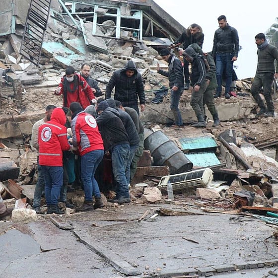 Röda korset volontärer tar ut människor ur raserat ut.