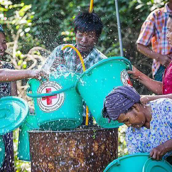 En grupp personer hämtar vatten ur brunn.