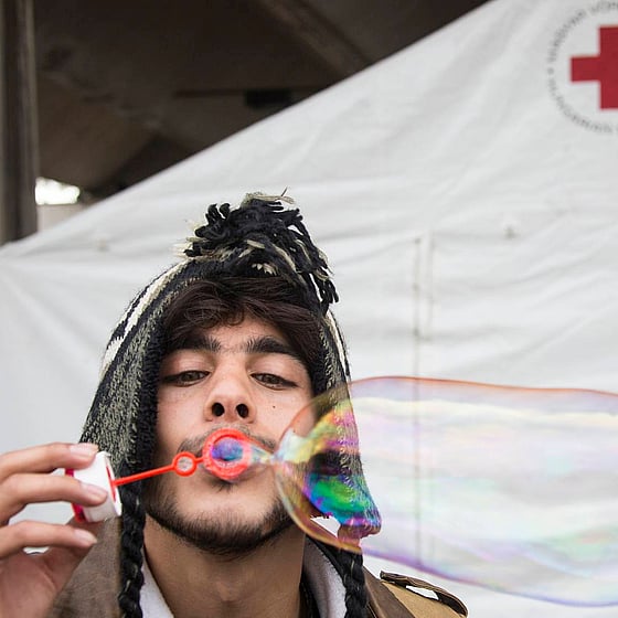 Man klädd i mössa blåser såpbubblor