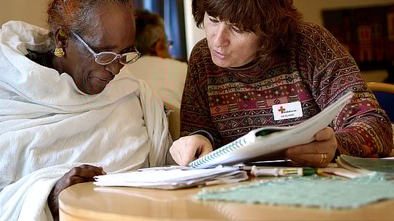 Frivillig rödakorsare tränar svenska med besökare på Träffpunkten i Uppsala.