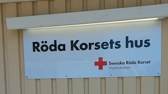 bild av gul husfasad med vit skylt där det står Röda Korsets hus 
