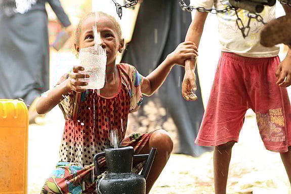 Flicka hämtar vatten från en kran.