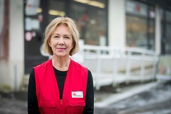 Kvinna i röd väst tittar rakt in i kameran.