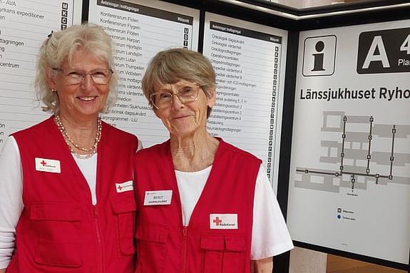 Två kvinnor står vid en anslagstavla.