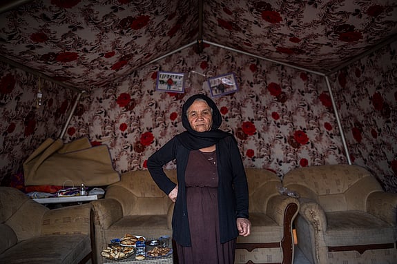 Kvinna boende i flyktingläger står inne i sitt tält.