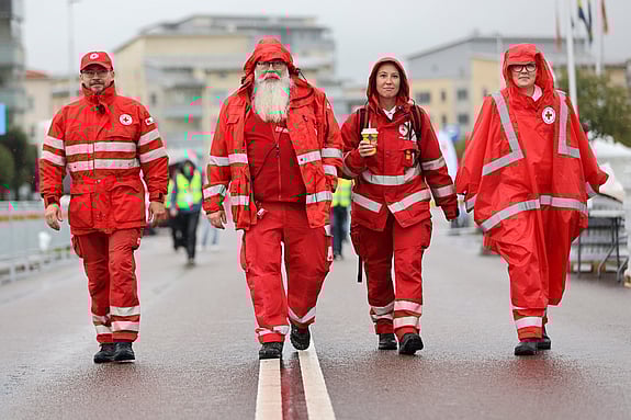 Fyra person vandrar på en väg, de har kläder på sig som visar att de kommer från Röda Korset.
