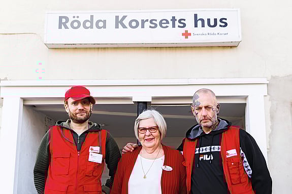 Tre rödakorsare står tillsammans framför Röda Korsets hus och tittar in i kameran.