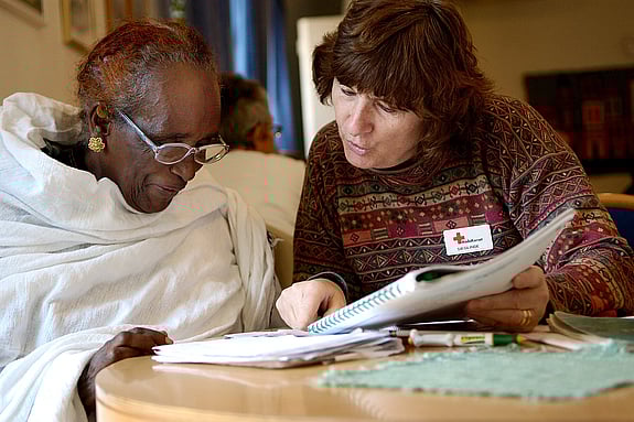 Frivillig rödakorsare tränar svenska med besökare på Träffpunkten i Uppsala.