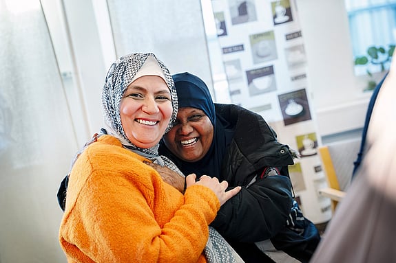 Två kvinnor håller om varandra och ser glada ut