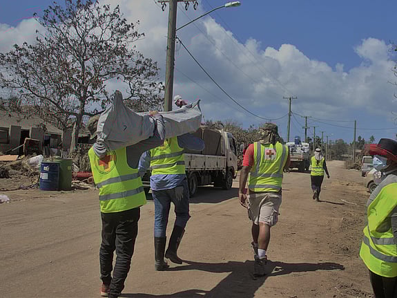 Röda Korset volontärer bär säckar med nödhjälp