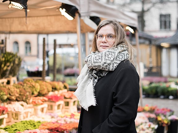 Johanna Lönn står på ett torg framför ett blomstånd.