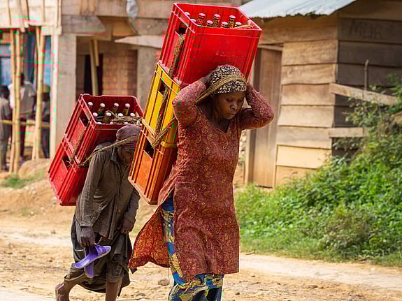 Kvinna och barn bär tungt på ryggen.