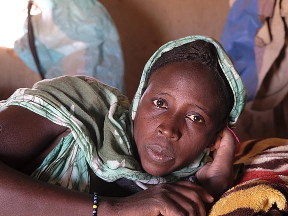 Kvinna i grön sjal tittar in i kameran