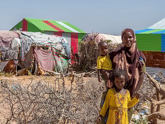 Mamma och barn framför tält.