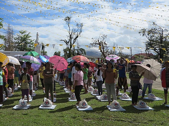 Flertalet personer under färgglada paraplyer och vimplar.