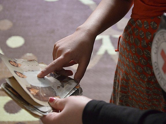 En hand pekar på fotografi av saknade familjemedlemmar.