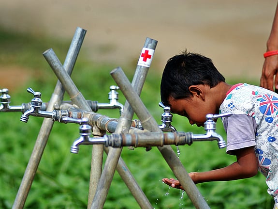 Pojke dricker vid vattenbrunn