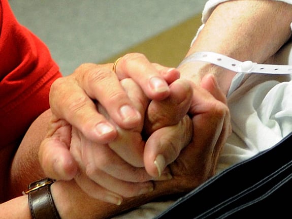 En volontärs hand håller i en patients hand