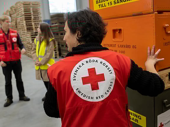 Volontär i Röda Korset väst lyfter kartonger med sjukvårdsmaterial.