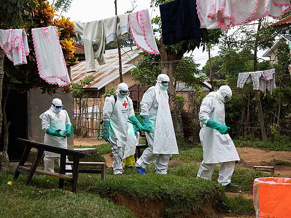 Människor i skyddsdräkt går igenom by