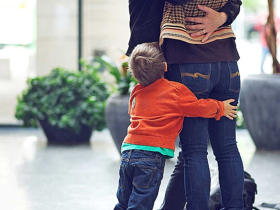 Liten pojke kramar om föräldrars ben