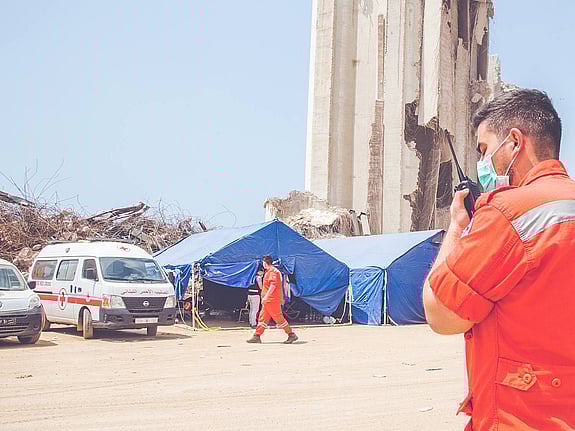 Röda korset volontär talar i komradio utanför tält