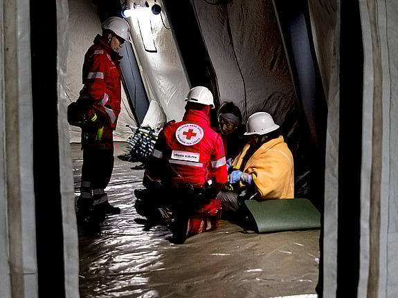 Två volontärer från Röda Korset hjälper två personer i ett tält under en krisövning.