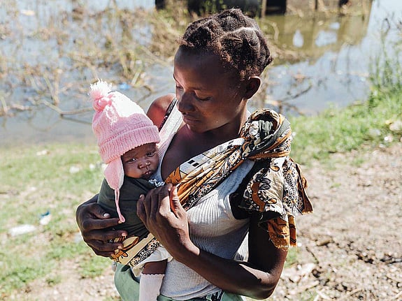 Mor bär på dotter i rosa mössa