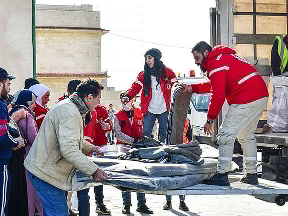 Röda korset volontärer hjälper människor ut raserat hus.