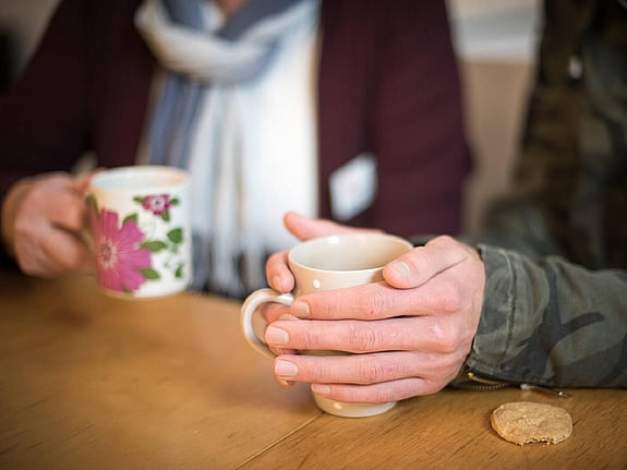 Händer och kaffemuggar.